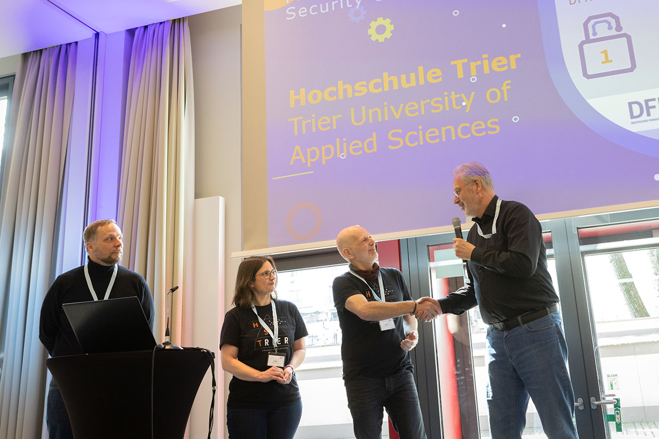 Das Foto zeigt die Preisverleihung der DFN-Security-Challenge bei der 82. DFN-Betriebstagung in Berlin. Zu sehen sind von links nach rechts: Ralf Gröper vom DFN-Verein, Tanja Rolinger und Ralf Becker von der Hochschule Trier,die den Preis entgegengenommen haben, sowie Jochem Pattloch vom DFN-Verein. Foto: Jürgen ALOIsius Morgenroth