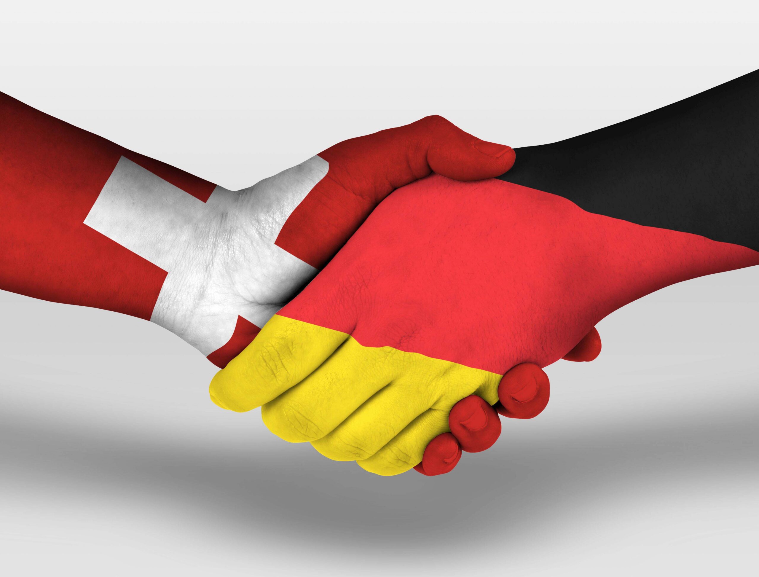 Zwei Hände im Handschlag. Die linke Hand ist in den Farben der Schweizer Flagge bemalt, die rechte in den Farben der deutschen Flagge. Das Motiv symbolisiert die Zusammenarbeit und das Peering zwischen den Wissenschaftsnetzen der Schweiz und Deutschlands. Foto: Adobe Stock